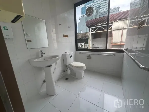Office Space for rent in Bang Rak, Bangkok - Clean tiled restroom with sink, toilet, grab bars, and a large exterior window.