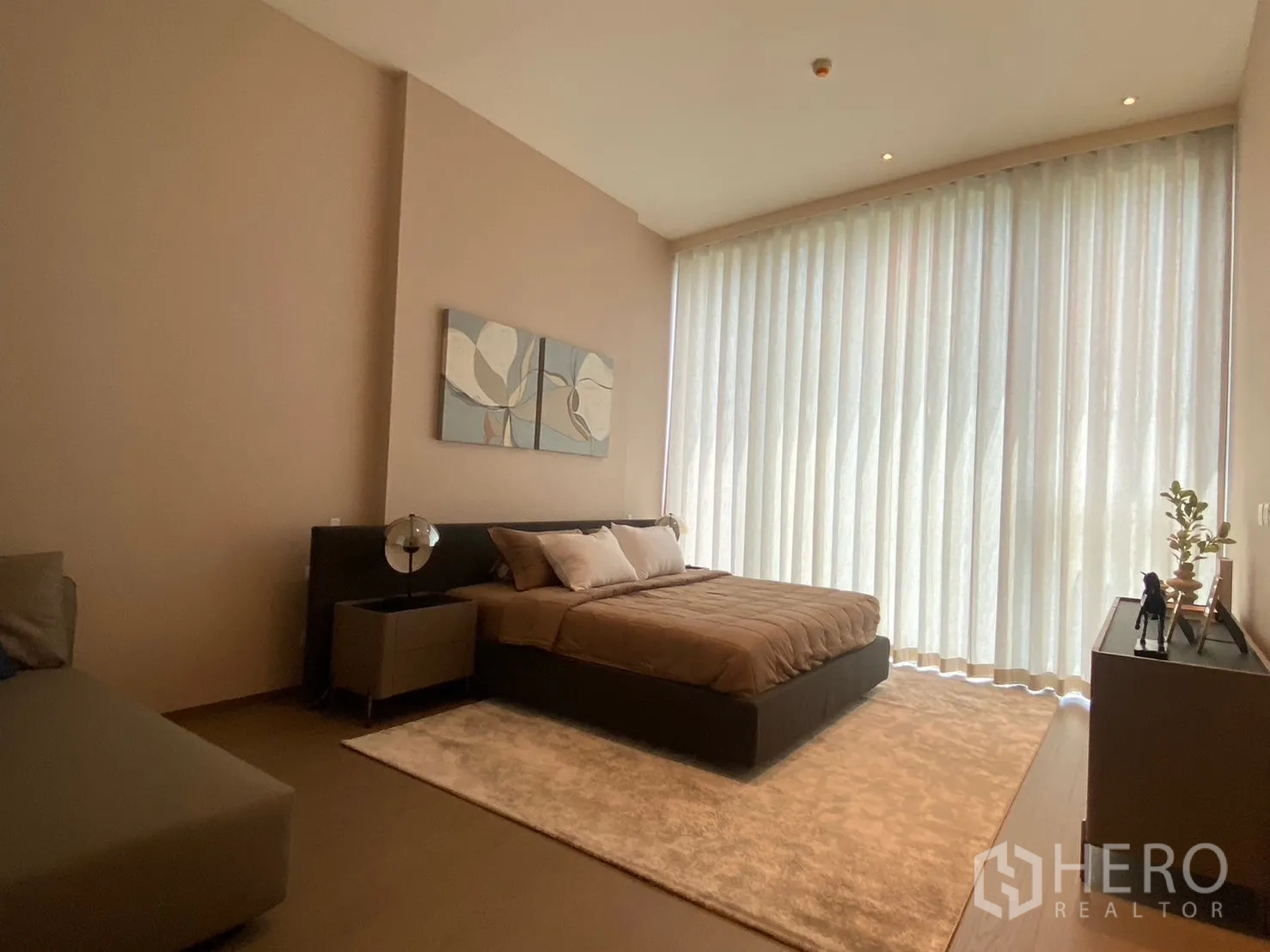 คอนโด for rent in Pathum Wan, Bangkok - ห้องนอนกว้างพร้อมม่านโปร่งสูงจรดเพดาน เตียงคิงไซส์ โต๊ะข้าง พรม และคอนโซลสมัยใหม่