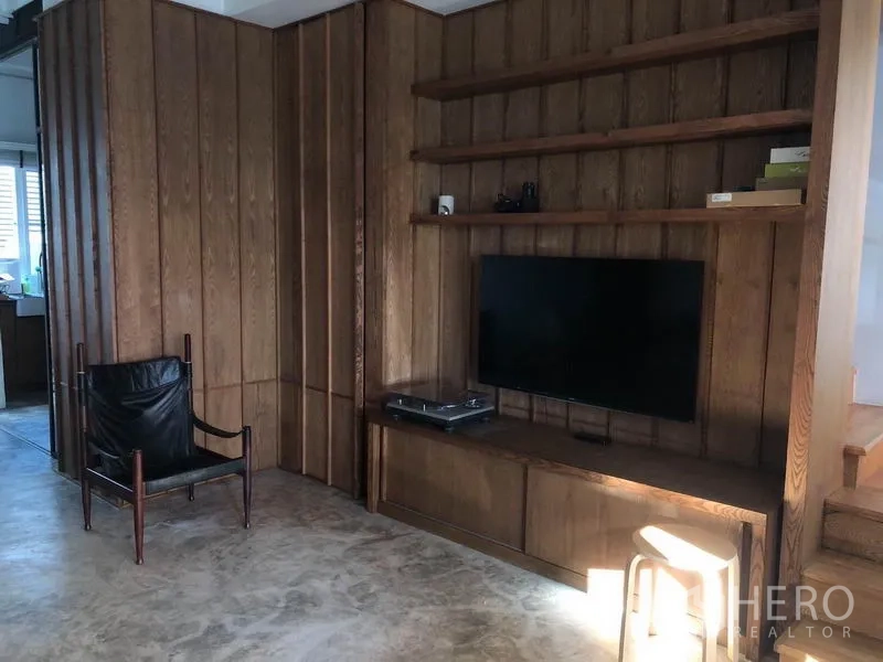 联排别墅 出售在Wang Thonglang, Bangkok - 客厅设木质电视墙与开放式置物架，地面为抛光水泥。