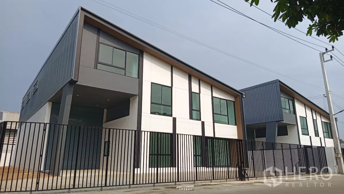 Warehouse for rent or sale in Lam Luk Ka, Pathum Thani - Modern warehouse units with sloped roofs and tall windows behind a black metal fence in Lam Luk Ka.