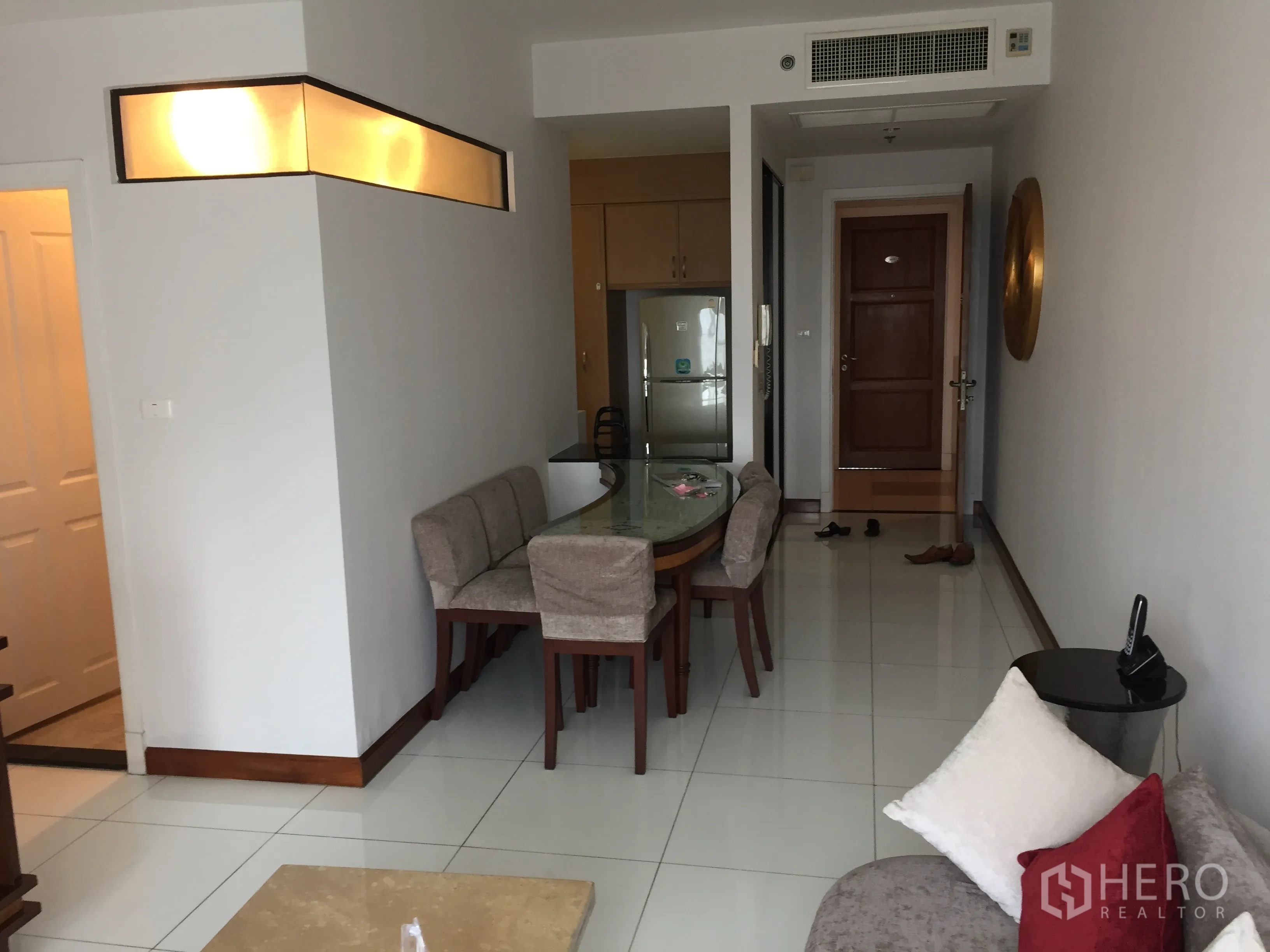 Condominium for rent in Watthana, Bangkok - Open-plan dining area and entry hall with a glass-top table and built-in storage.