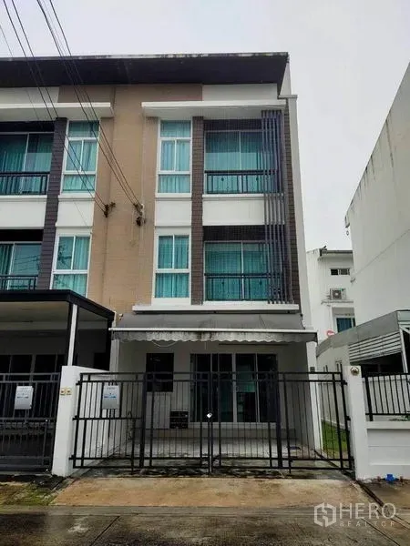 Townhouse for rent in Wang Thonglang, Bangkok - Modern three-storey townhouse exterior with gated parking and tall windows in Wang Thonglang, Bangkok.