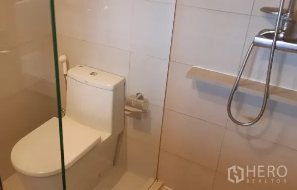 Condominium for rent in Khlong Toei, Bangkok - Clean bathroom with glass-enclosed shower, handheld showerhead and modern toilet.