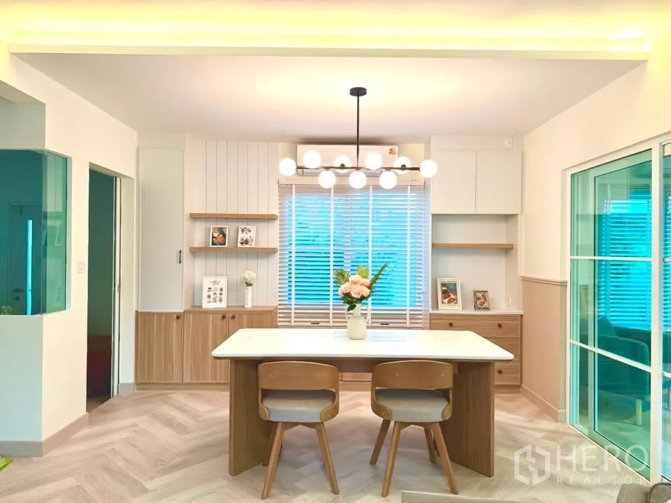 Detached House for rent in Bang Phli, Samut Prakan - Dining area with modern chandelier, built-in storage, and large table.
