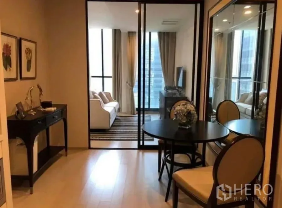 Condominium for rent in Pathum Wan, Bangkok - Compact dining nook with round table and chairs beside a mirrored cabinet and sliding glass doors.