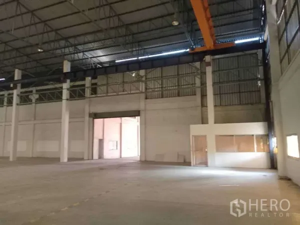 Factory for rent in Mueang Samut Prakan, Samut Prakan - Spacious factory interior with high ceiling, steel trusses, gantry crane and an attached glass-partitioned office.