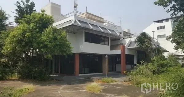 Home Office for rent in Huai Khwang, Bangkok - Two-storey home office with sloped roof, large glass windows and mature trees.
