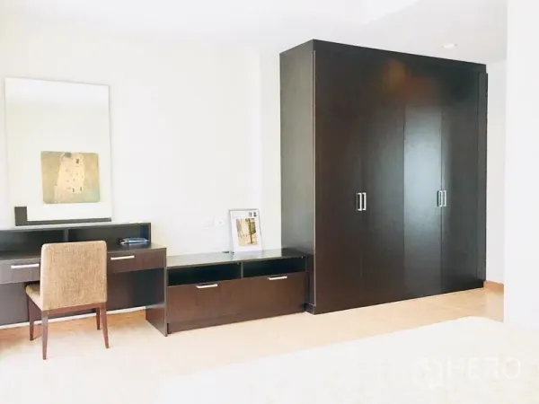联排别墅 出租在Prawet, Bangkok - 卧室一角，深色衣柜、梳妆台和椅子。