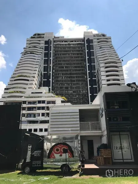 Condominium for rent in Watthana, Bangkok - High-rise white condominium exterior with tiered balconies under a bright blue sky.