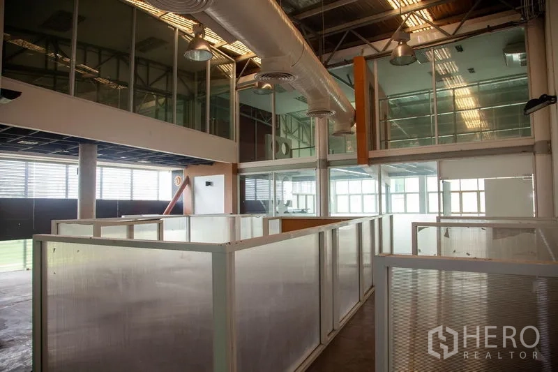 Warehouse for rent in Prawet, Bangkok - Double-height warehouse in Prawet, Bangkok with glass mezzanine offices, exposed ducting and partitioned work bays.