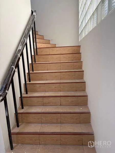 Standalone for rent in Khlong Toei, Bangkok - Internal tiled staircase with metal handrail and glass block wall.