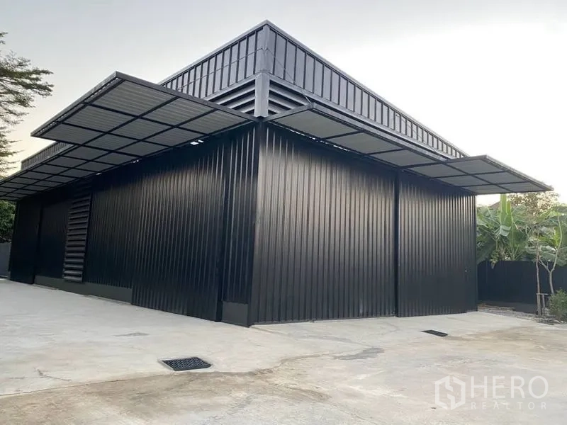 โกดัง for rent in Bang Kapi, Bangkok - ภายนอกโกดังผนังเมทัลชีท ประตูทางเข้ากว้าง กันสาดรอบอาคาร และลานคอนกรีต