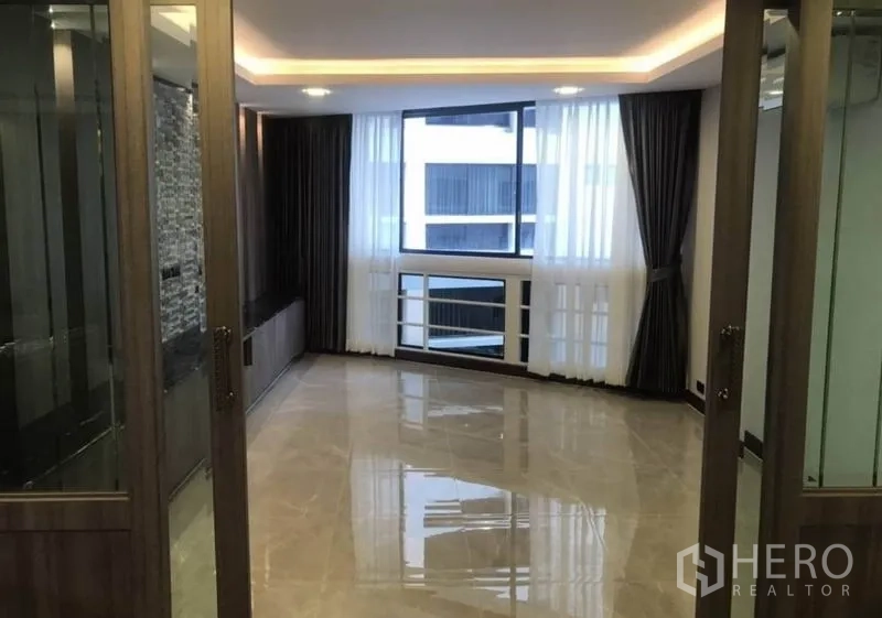 Condominium for rent in Khlong Toei, Bangkok - Bright living area with large window, glossy tile floor and glass doors.