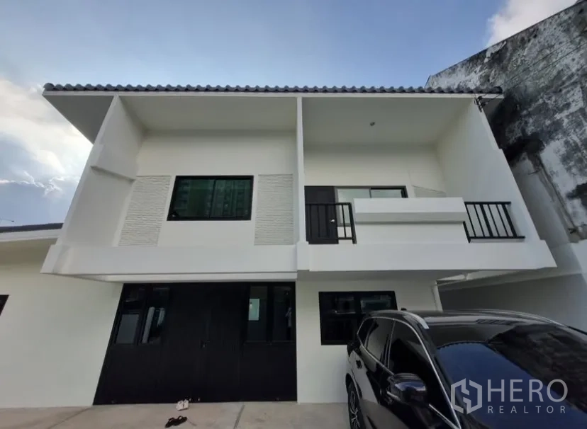 Detached House for rent in Suan Luang, Bangkok - Front facade with twin balconies, black-framed windows and parking area.