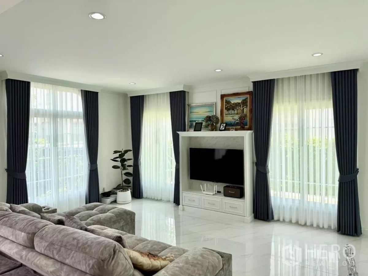 บ้าน ให้เช่าในBang Phli, Samut Prakan - ห้องนั่งเล่นสว่าง ผ้าม่านโปร่ง โซฟาขนาดใหญ่ และตู้ทีวีโทนขาวโมเดิร์น
