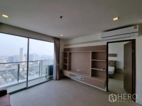 公寓 出租在Watthana, Bangkok - 客厅设定制电视墙、空调与观景阳台，旁边是通往卧室的门。