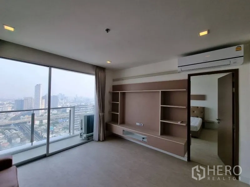 公寓 出租在Watthana, Bangkok - 客厅设定制电视墙、空调与观景阳台，旁边是通往卧室的门。