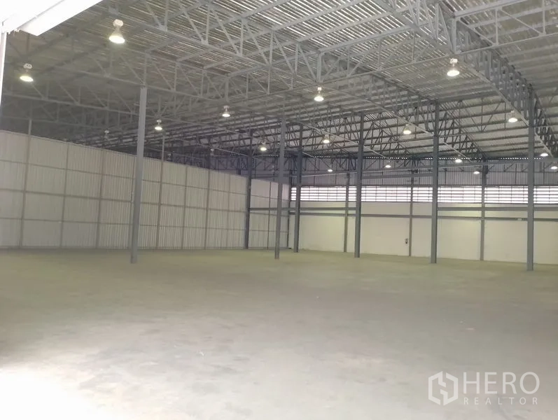 货栈 出租在Bang Phli, Samut Prakan - 仓库内部空间宽敞，钢结构高挑屋顶，明亮高架灯与平整混凝土地面。