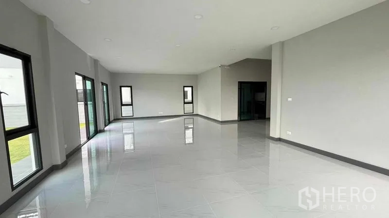 Detached House for sale in Bang Phli, Samut Prakan - Spacious open-plan living area with glossy tiles and sliding doors to the garden.