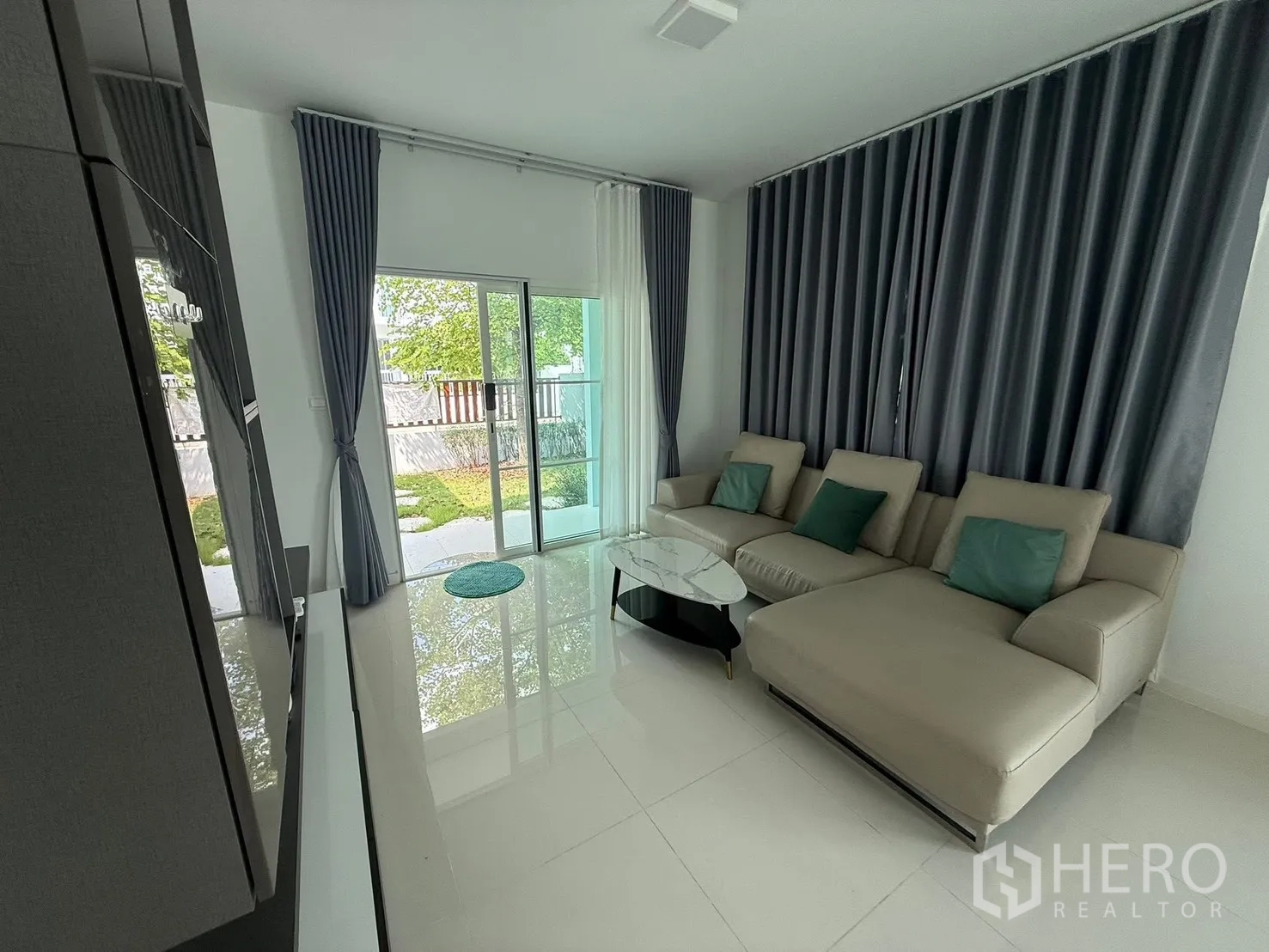 บ้านเดี่ยว for rent in Bang Phli, Samut Prakan - ห้องนั่งเล่นมีประตูกระจกบานเลื่อนออกสู่สวนและผ้าม่านทึบยาวจรดพื้น