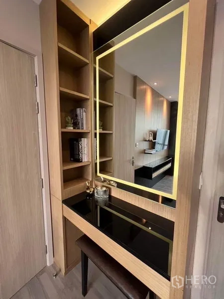 Condominium for sale in Bang Sue, Bangkok - Built-in dressing nook with backlit mirror, open shelves and bench in light wood.