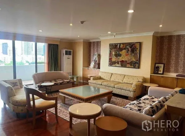 公寓 出租在Watthana, Bangkok - 宽敞客厅，多个沙发与玻璃茶几，墙面装饰画，推拉门通向观景阳台。