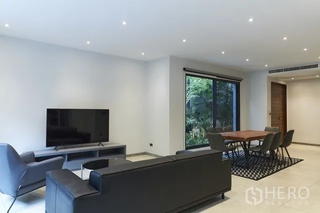 Townhouse for sale in Watthana, Bangkok - TV lounge and dining area with a large window to the private garden.