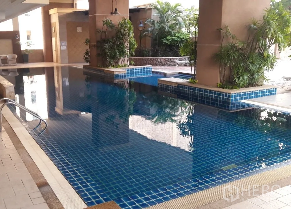 公寓 出租在Watthana, Bangkok - 公寓配套蓝色马赛克泳池，绿植环绕并设休憩区。