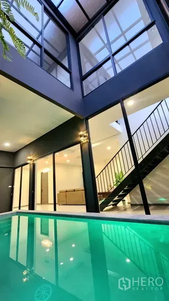 独立式住宅 出售在Khlong Toei, Bangkok - 私家泳池庭院，四周玻璃墙与金属楼梯，灯光温暖。