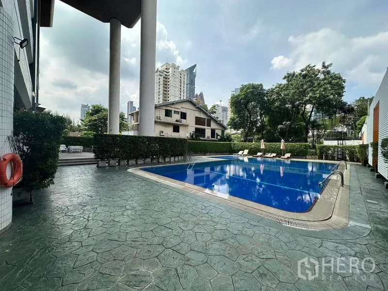 公寓 出租在Watthana, Bangkok - 公寓室外泳池，配躺椅并被绿意环绕。