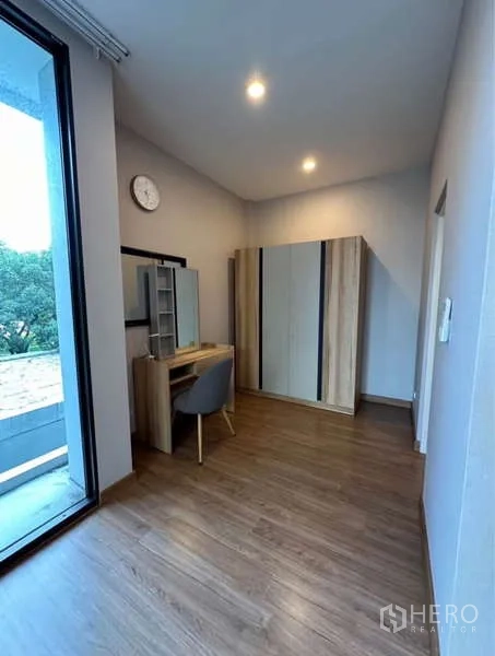 Townhouse for rent in Lat Phrao, Bangkok - Dressing area with wardrobe, vanity desk and sliding door to the balcony.