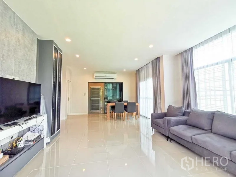 บ้าน ให้เช่าหรือขายในPrawet, Bangkok - ห้องนั่งเล่นปูกระเบื้องเงา โซฟาสีเทา ชุดโต๊ะอาหาร และหน้าต่างบานใหญ่