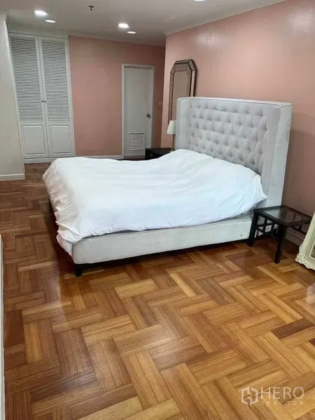 Condominium for sale in Bangkok - Spacious bedroom with tufted headboard, parquet wood floors and built-in wardrobe.