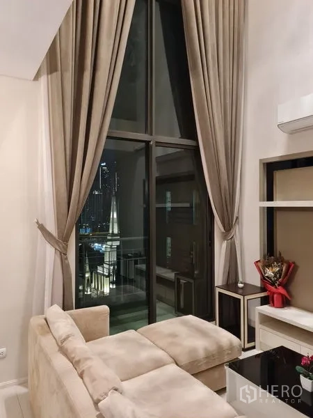 公寓 出售在Ratchathewi, Bangkok - 夜景客厅一角，落地窗帘、沙发与小阳台