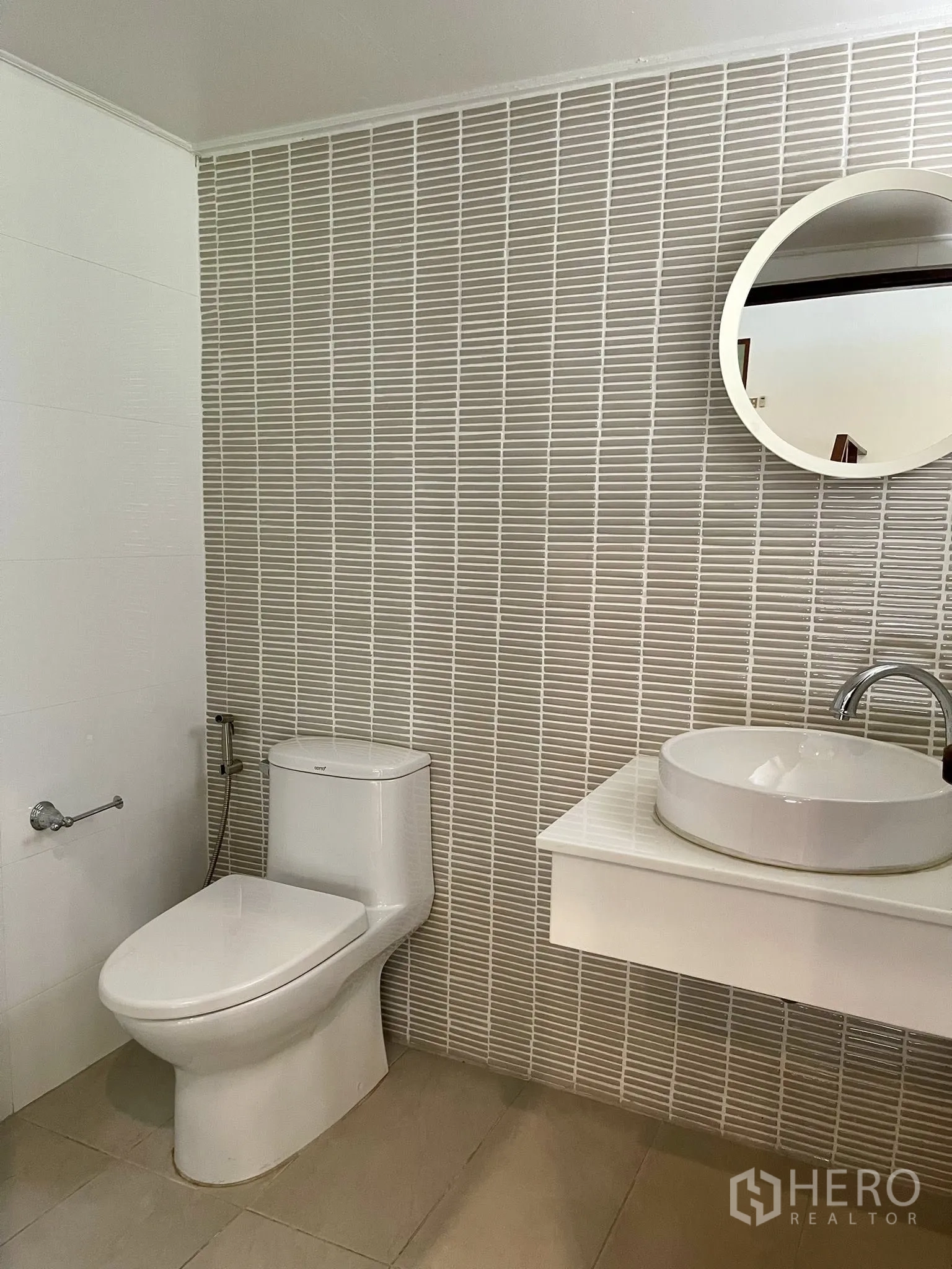 Detached House for rent in Pathum Wan, Bangkok - Modern bathroom with white tiles, a round mirror, and toilet.