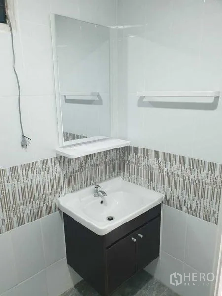 Warehouse for rent in Prawet, Bangkok - Modern bathroom vanity with mirror and tiled wall inside the warehouse office.