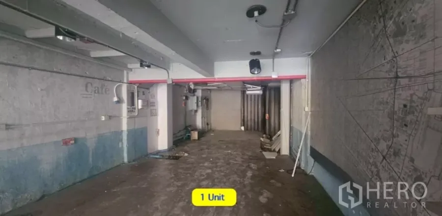 店屋 出租在Watthana, Bangkok - 一层开放式空间，水泥地面与外露管线，后方金属卷闸门。