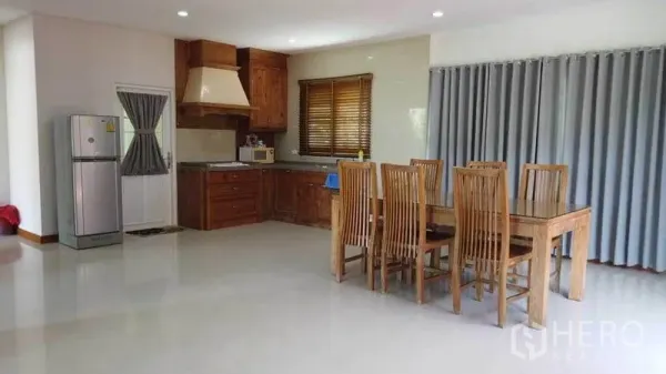 独立式住宅 出租或出售在Pak Kret, Nonthaburi - 开放式用餐区与木质橱柜厨房、冰箱及六人餐桌，配落地窗帘。