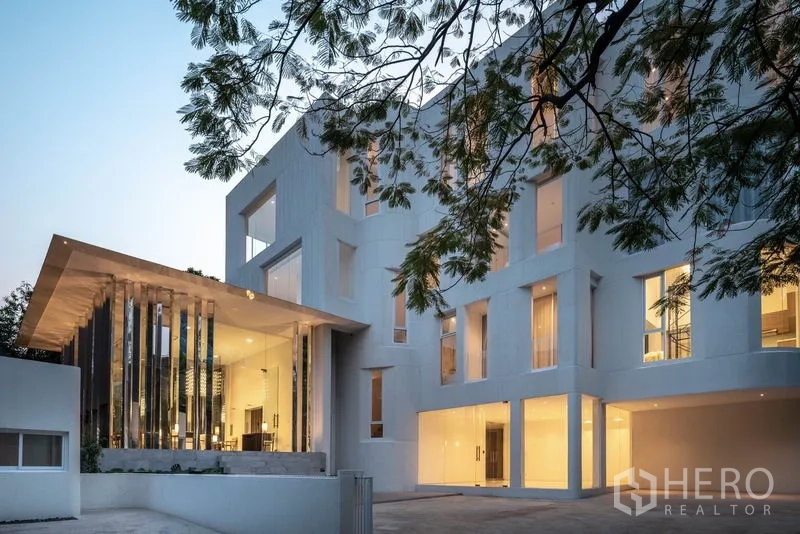 Condominium for rent in Khlong Toei, Bangkok - Contemporary low‑rise condominium exterior with illuminated lobby at dusk.