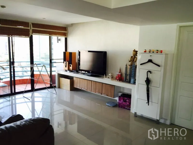 Condominium for rent in Bang Rak, Bangkok - TV room opening to a balcony with long media console and glossy tiled flooring.