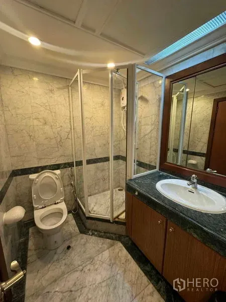公寓 出租在Pathum Wan, Bangkok - 大理石卫浴，配玻璃淋浴房、洗手台与马桶。