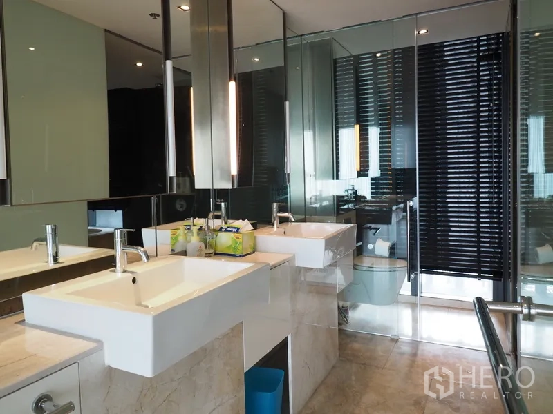 Condominium for rent in Sathon, Bangkok - Luxury bathroom with double vanities, large mirrors and a glass shower enclosure.