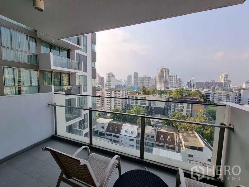 公寓 出租在Watthana, Bangkok - 带顶棚的阳台，玻璃栏杆与户外椅，视野开阔。