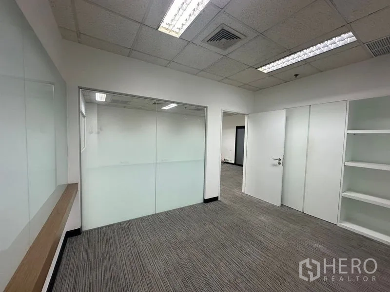 办公空间 出租在Watthana, Bangkok - 明亮的办公室入口，带磨砂玻璃会议室、内置书架与地毯砖。