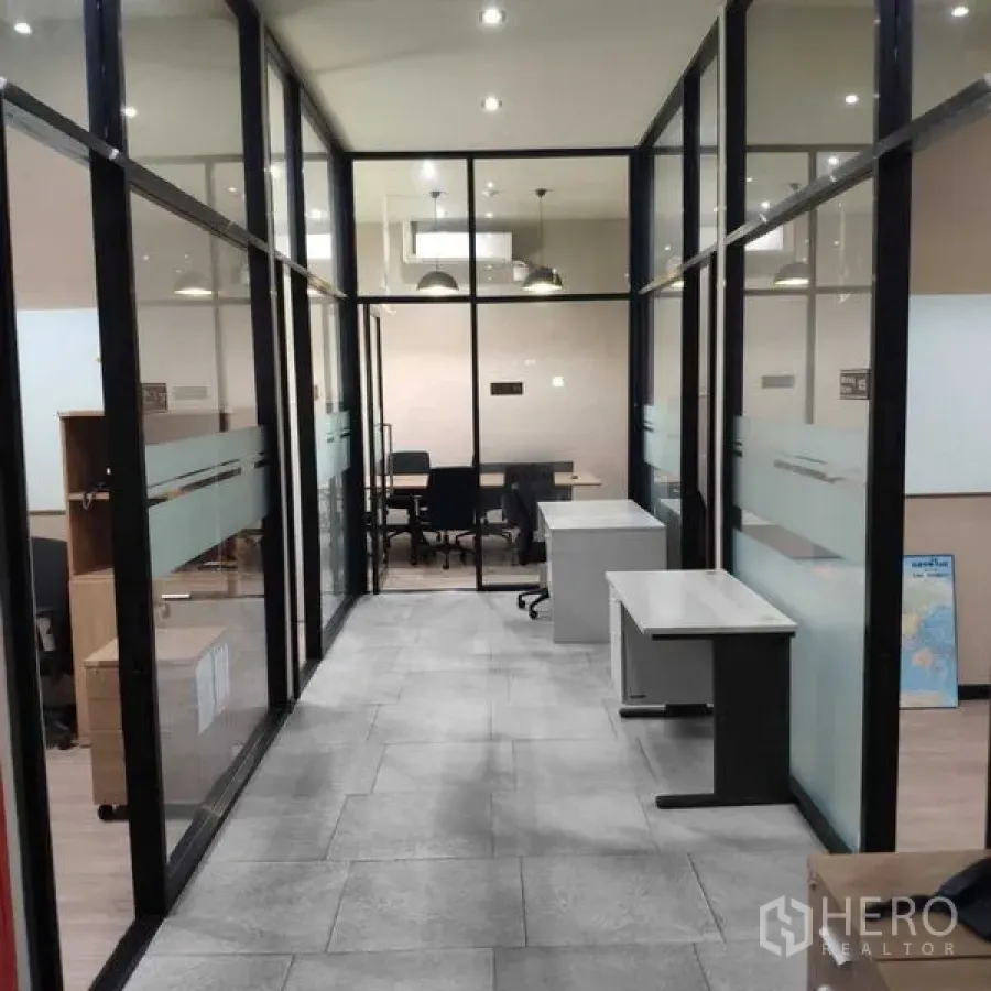 Office Space for rent - Narrow corridor past private glass offices with desks and pendant lights.