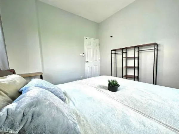 Detached House for rent in Lat Krabang, Bangkok - Bedroom angle showing bed, door and an open metal shelving unit on a pale wall.