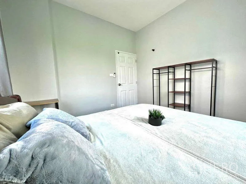 Detached House for rent in Lat Krabang, Bangkok - Bedroom angle showing bed, door and an open metal shelving unit on a pale wall.