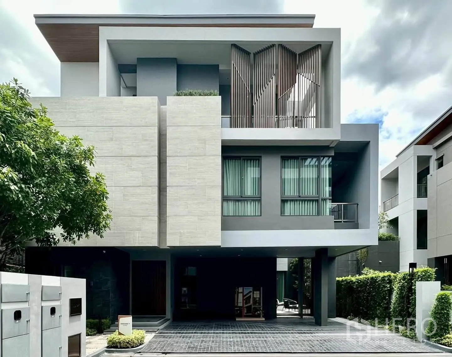 独栋房屋 for rent or sale in Suan Luang, Bangkok - 现代三层独栋外立面，几何线条、大窗与车位及绿篱。