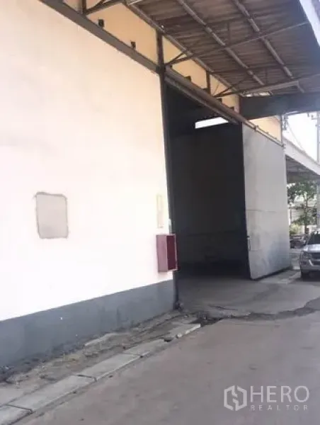 货栈 出租在Chachoengsao - 侧面入口高门，墙挂消防箱，带顶装卸区域。