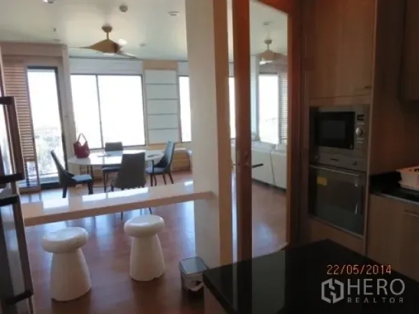 Condominium for rent in Bang Rak, Bangkok - View from the kitchen to a bright dining and living area with large windows.